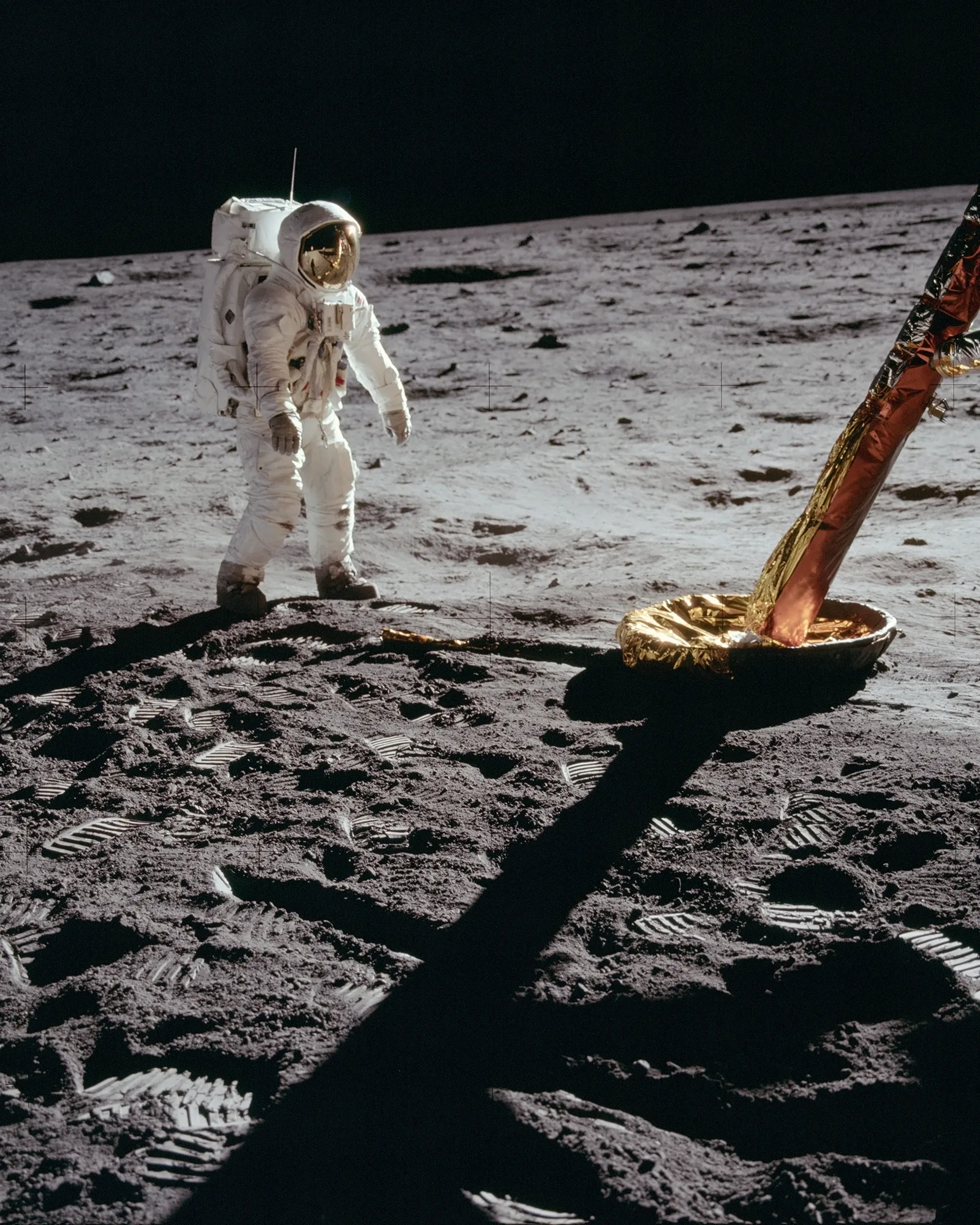 Astronaut standing on the moon beside the lunar module, surrounded by boot prints